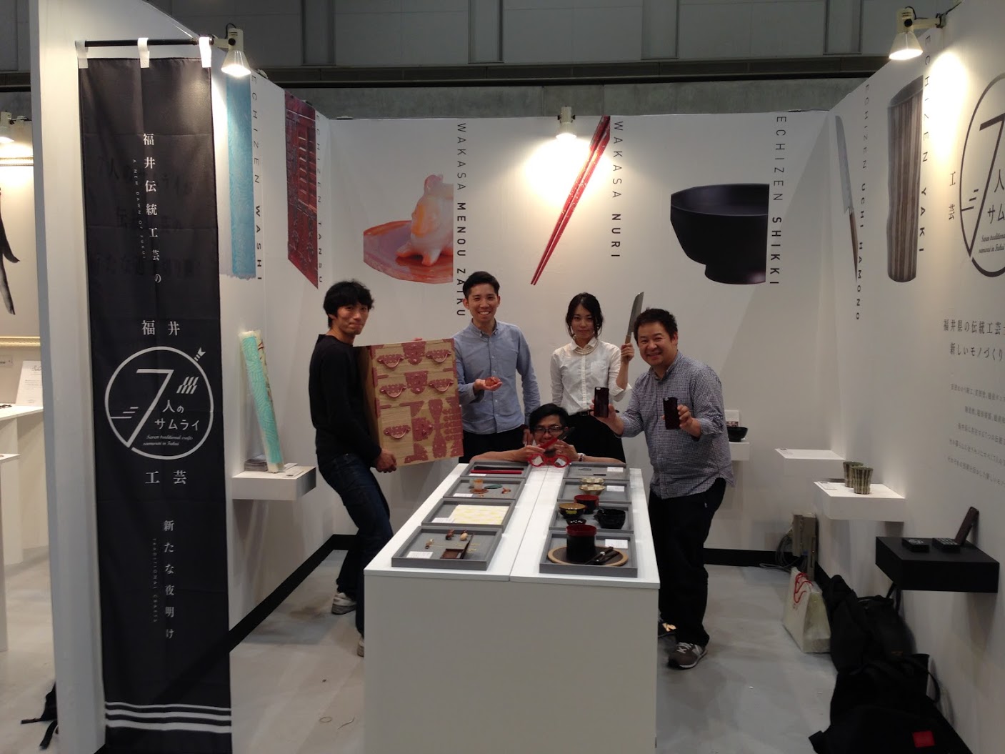 福井の伝統工芸展示会の様子を描いた画像。越前漆器、越前和紙、越前打刃物など、福井県を代表する工芸品が並び、職人たちが手掛けた美しい作品や技術が紹介されている。